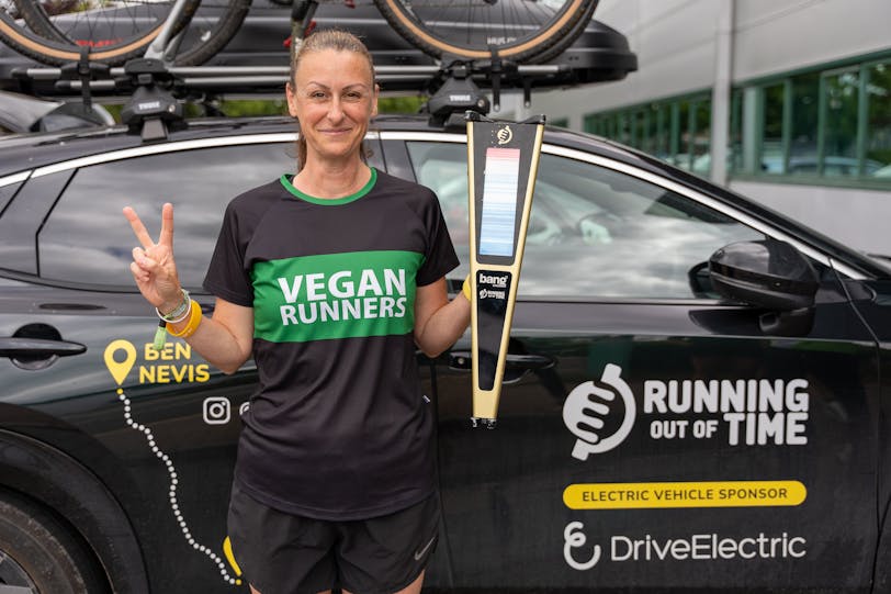 Victoria Hatch, Running Out of Time relay stage runner, with the all-electric Nissan Ariya support team vehicle sponsored by DriveElectric.