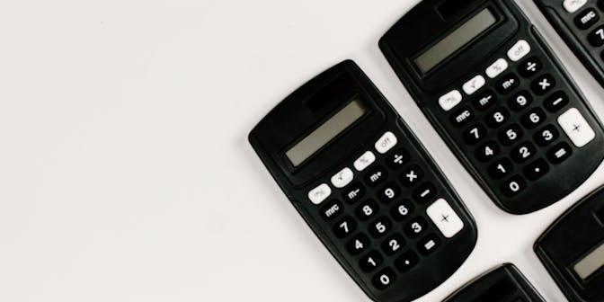 Black calculators on plain background