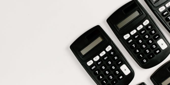 Black calculators on plain background