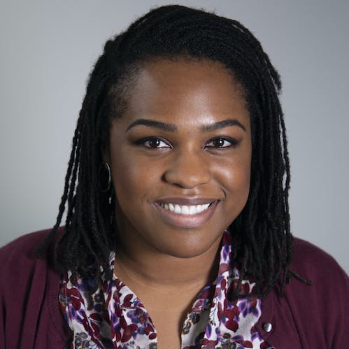 An headshot of Sarah Anoke with long hair and red clothing