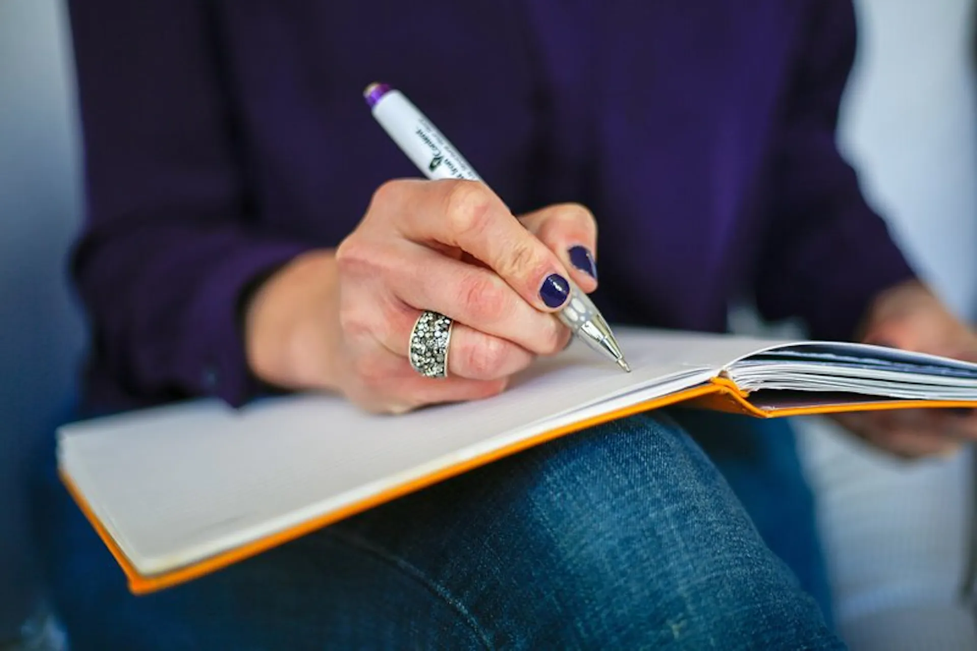 Person writing in a notebook with a pen