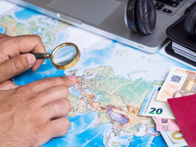 Man looking at a map with magnifying glass for global finances and transactions