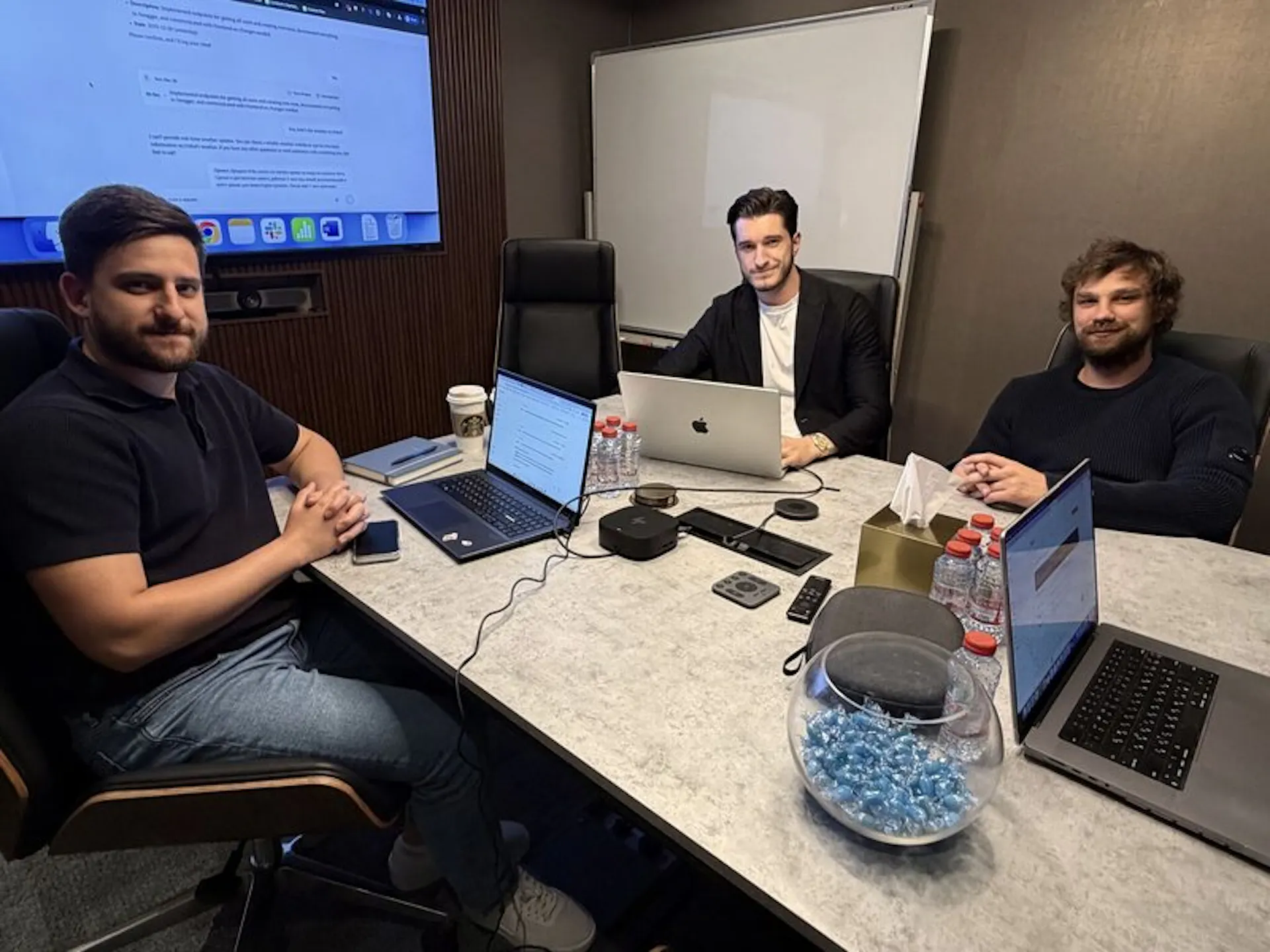 Team discussing work around a meeting table with laptops