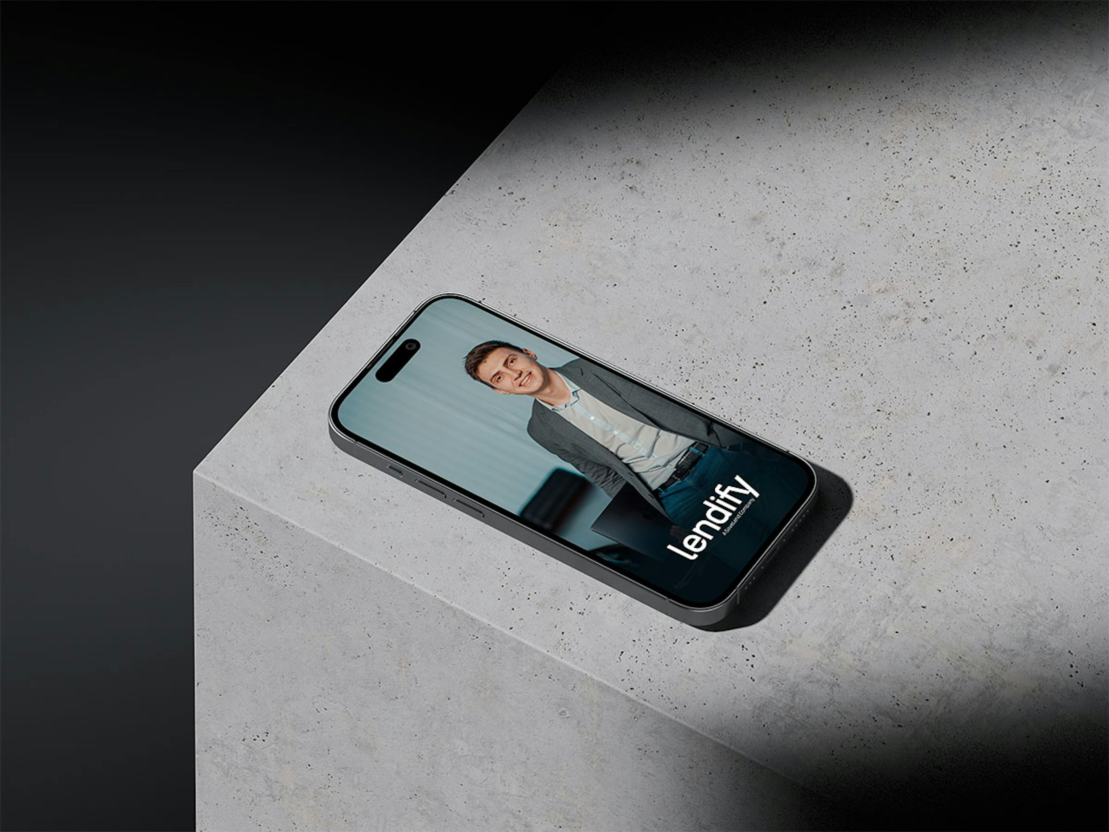 An iPhone sitting on a concrete surface displaying an Lendify ad