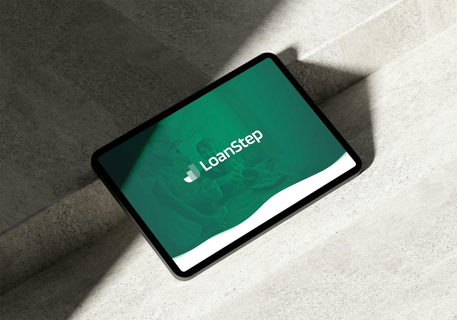 An iPad resting on a concrete surface in a sunny setting with hard shadows