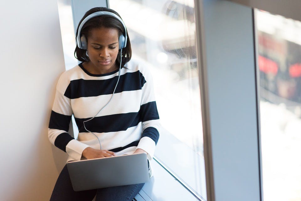 A person wearing headphones sitting by a window on their laptop during an Inkblot therapy session.