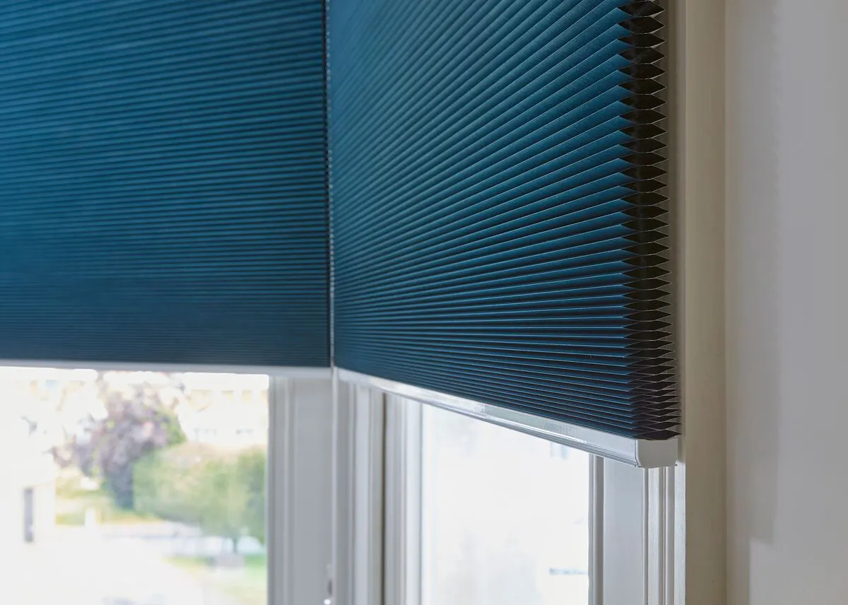 Close up of half opened blue Duette® honeycomb blinds on a window