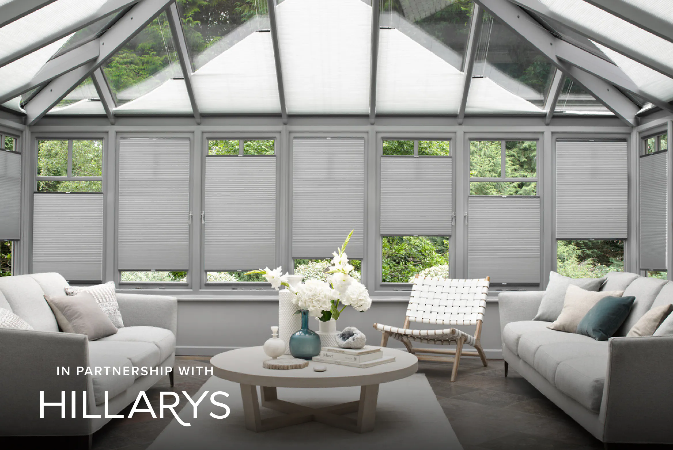 Light grey Duette® honeycomb blinds on gable‑end windows in a modern conservatory‑style living room.
