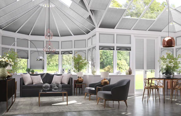 Light grey Duette® honeycomb blinds on gable‑end windows in a modern conservatory‑style living room joined with dining space