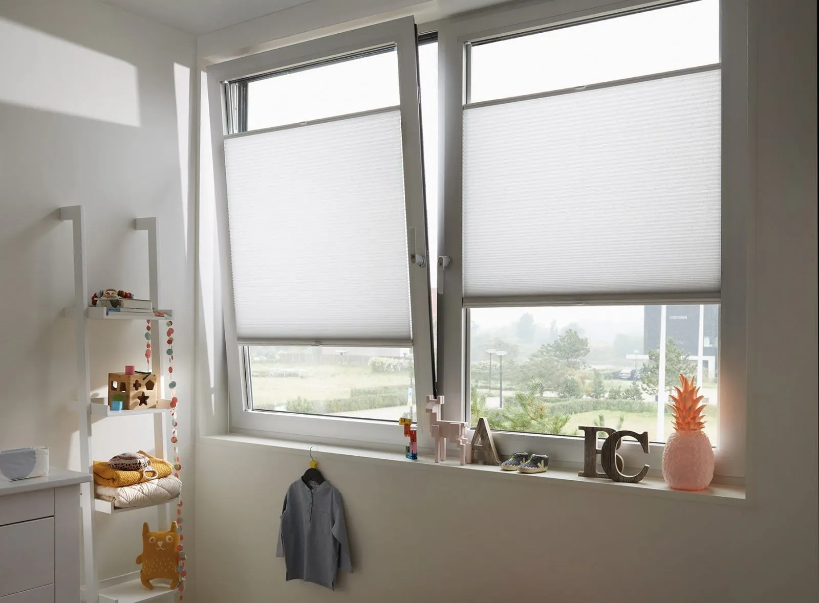 White Duette® honeycomb blinds on a slightly opened tilt and turn window in a light children's room
