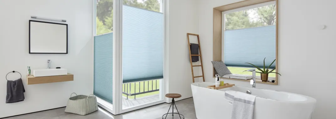 Light blue Duette® honeycomb top down bottom up blinds on windows in a modern white bathroom