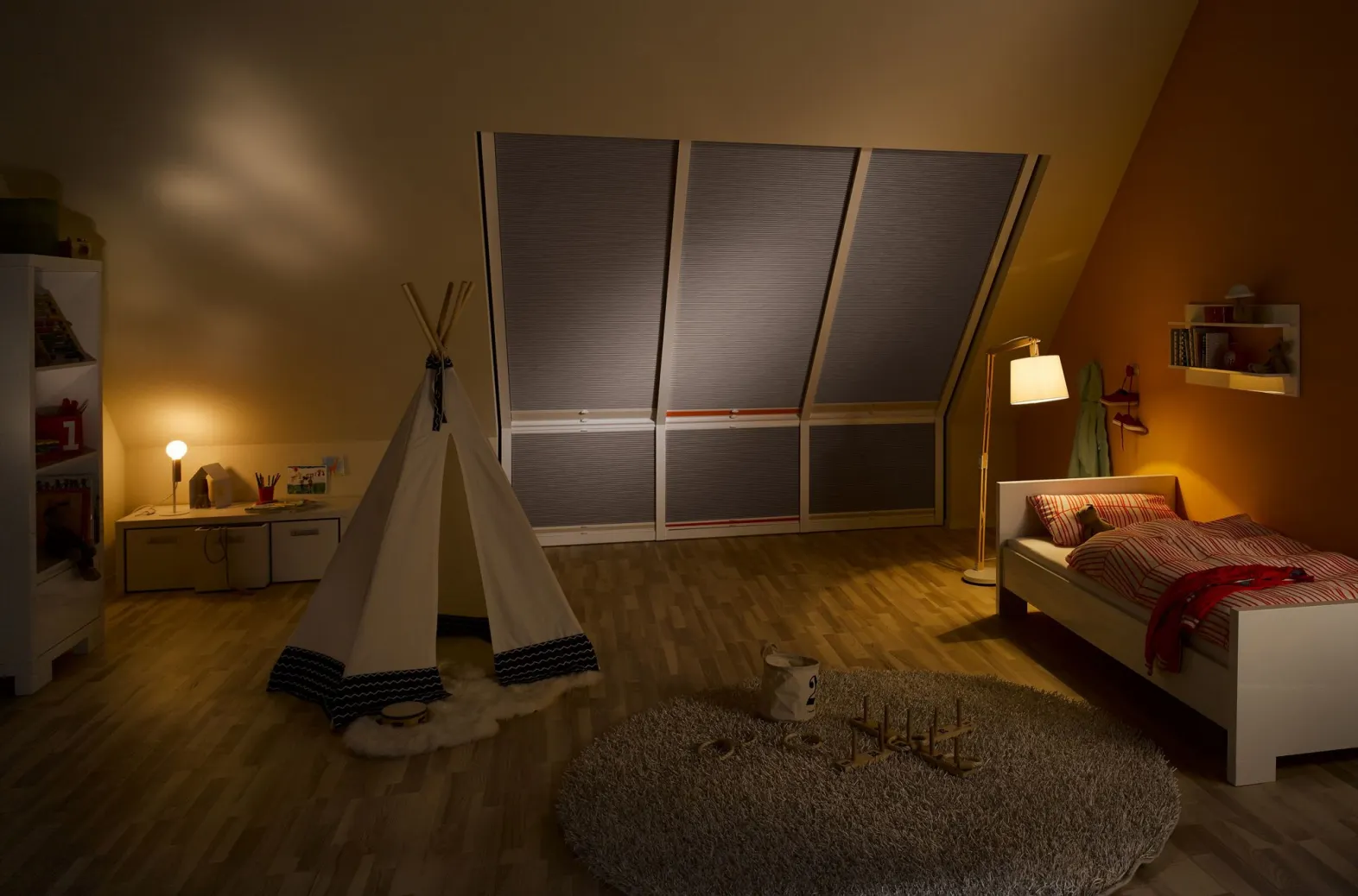 Children’s bedroom at night with fully closed Duette® honeycomb blinds on large slanted windows and warm lighting.