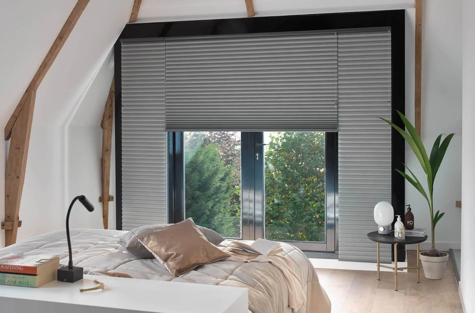 Grey Duette® honeycomb blinds covering a large bedroom window with modern decor and natural light.