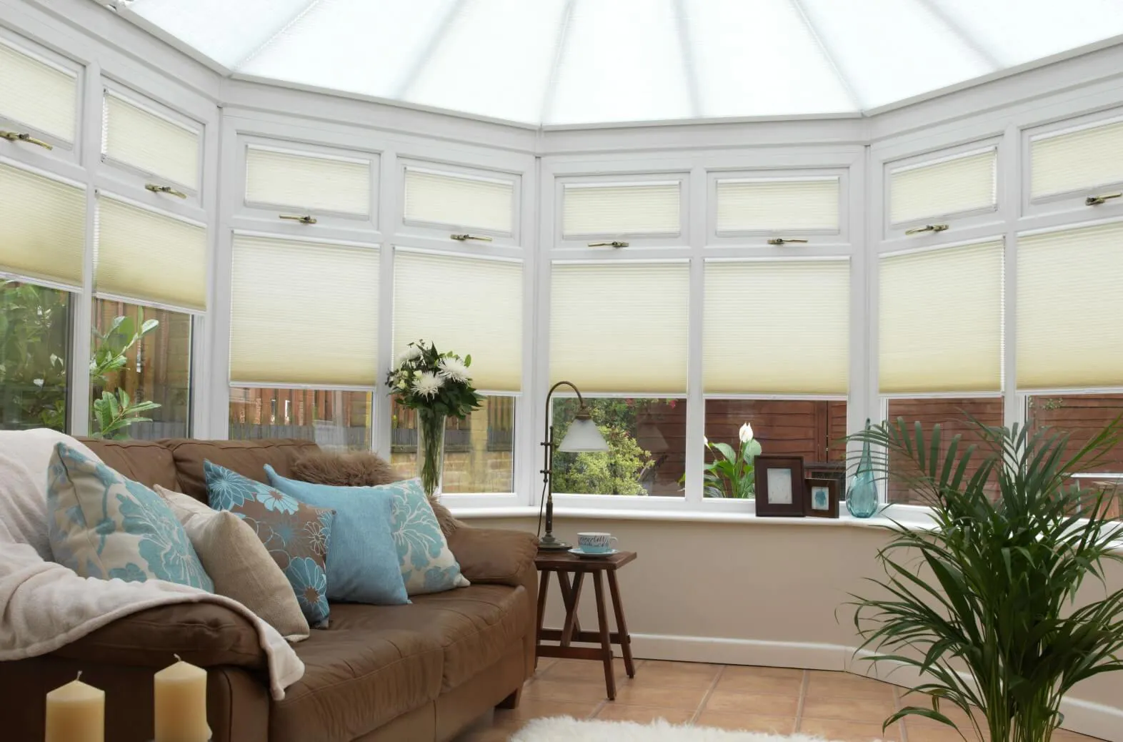 Soft almond Duette® honeycomb blinds on conservatory windows filling the room with warm, gentle light.