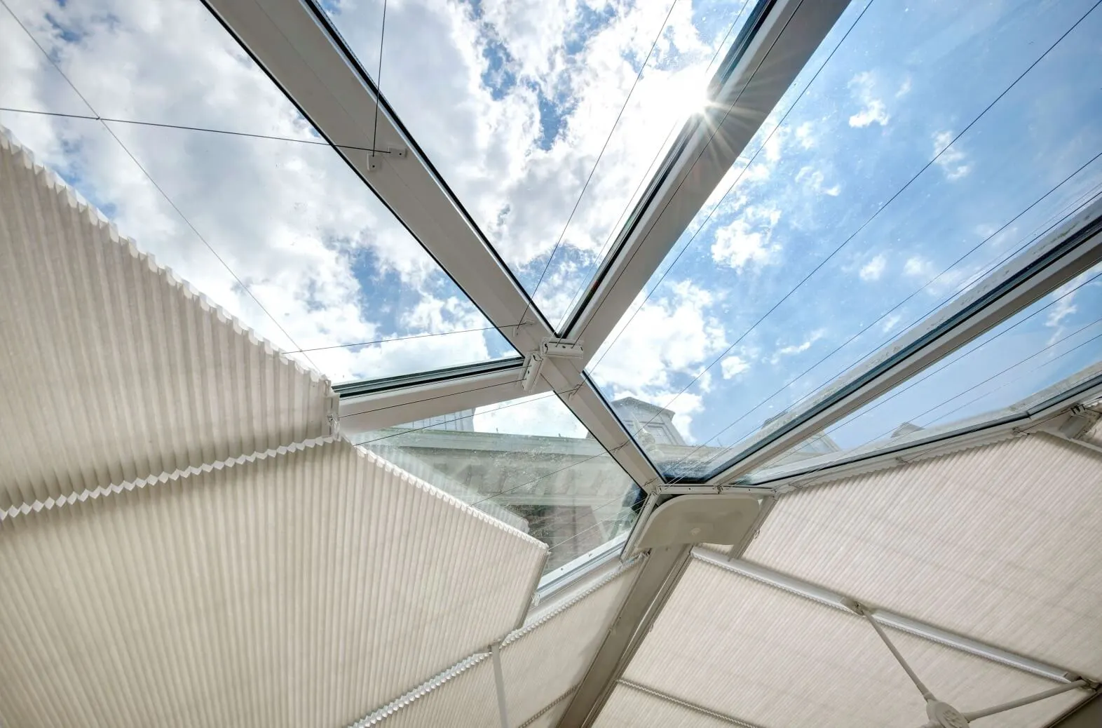 Neutral Duette® honeycomb blinds fitted to shaped conservatory roof windows under bright daylight.