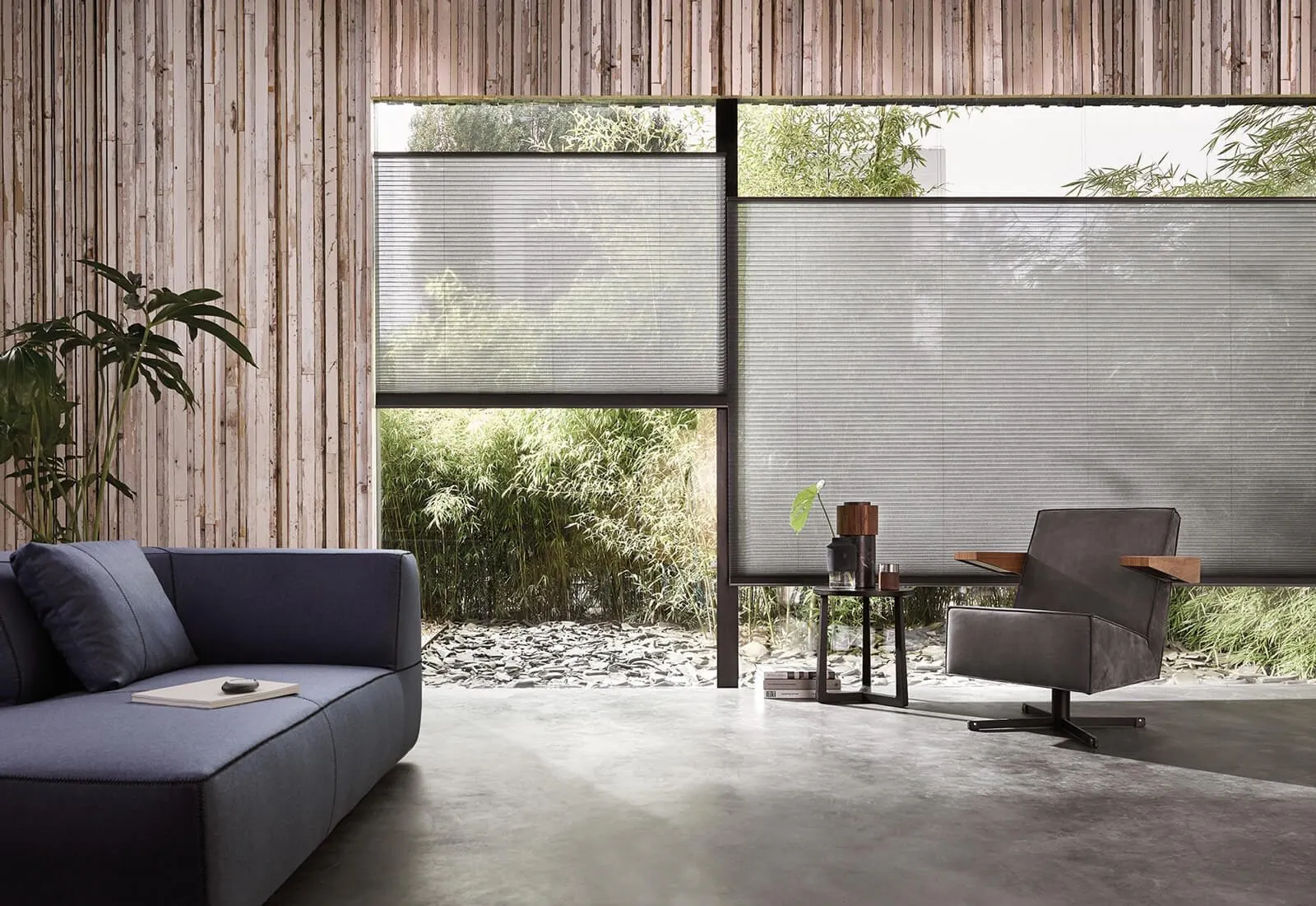Grey Duette® honeycomb blinds on large modern windows with a view of a bamboo garden.