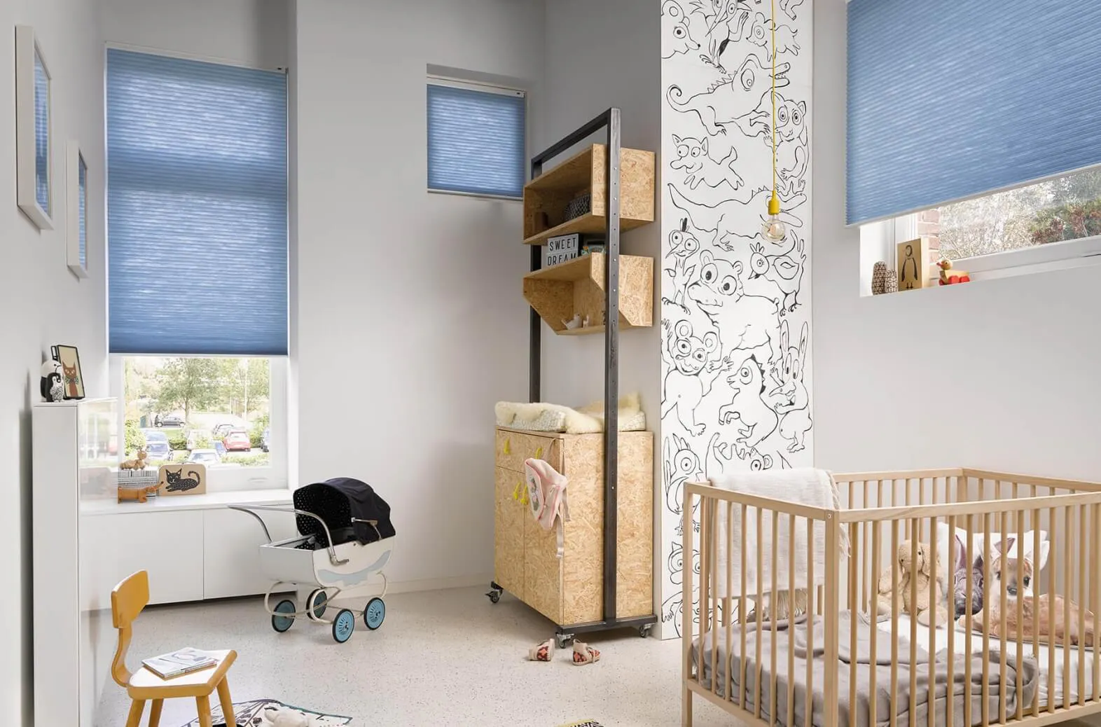 Light blue Duette® honeycomb blinds in a bright nursery with wooden furniture.