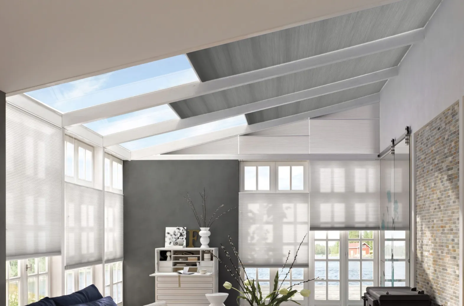 Grey Duette® honeycomb blinds on large roof and wall windows in a bright loft‑style room.