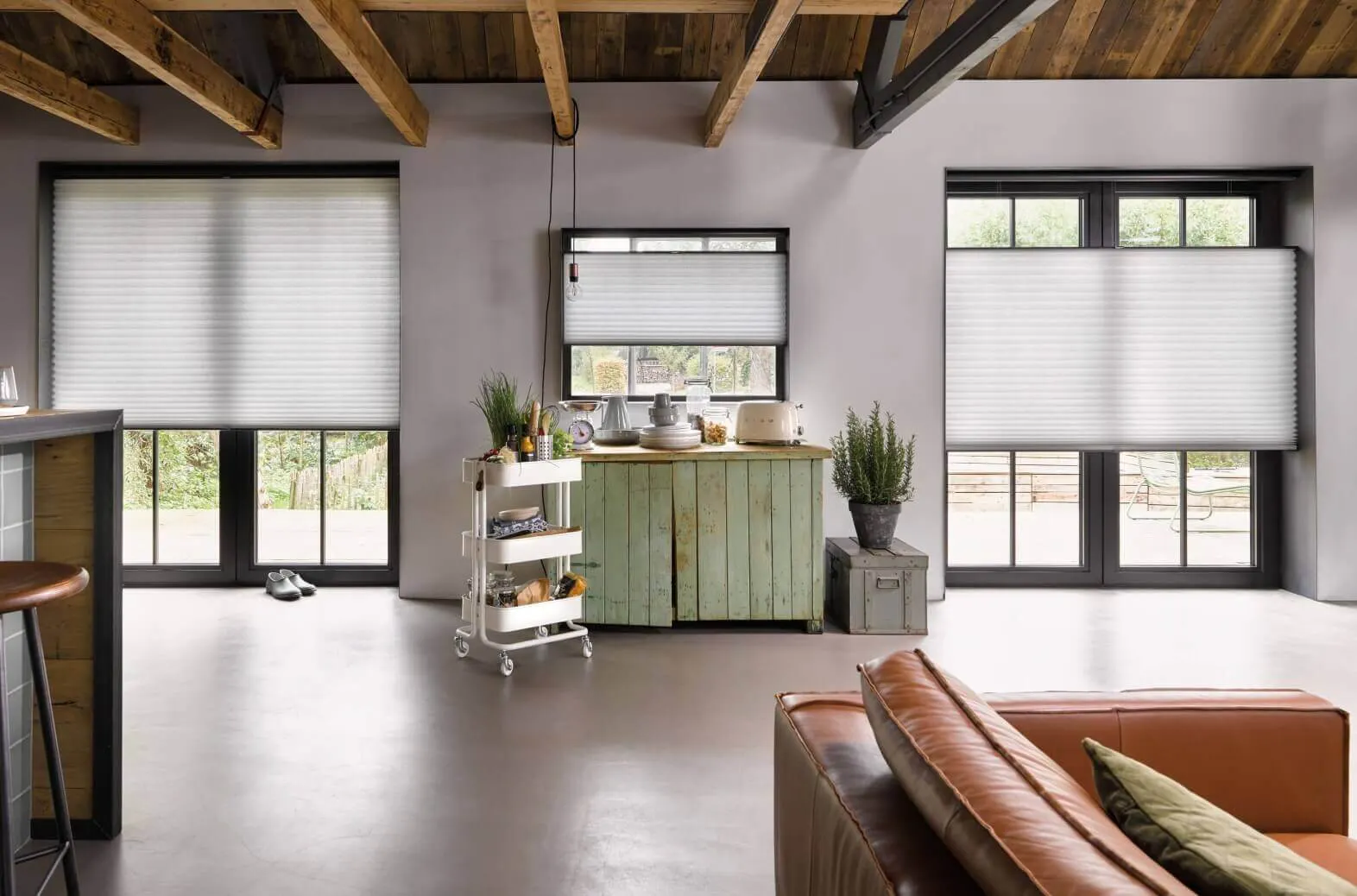 White Duette® honeycomb blinds on patio doors and windows in a rustic open‑plan living space.