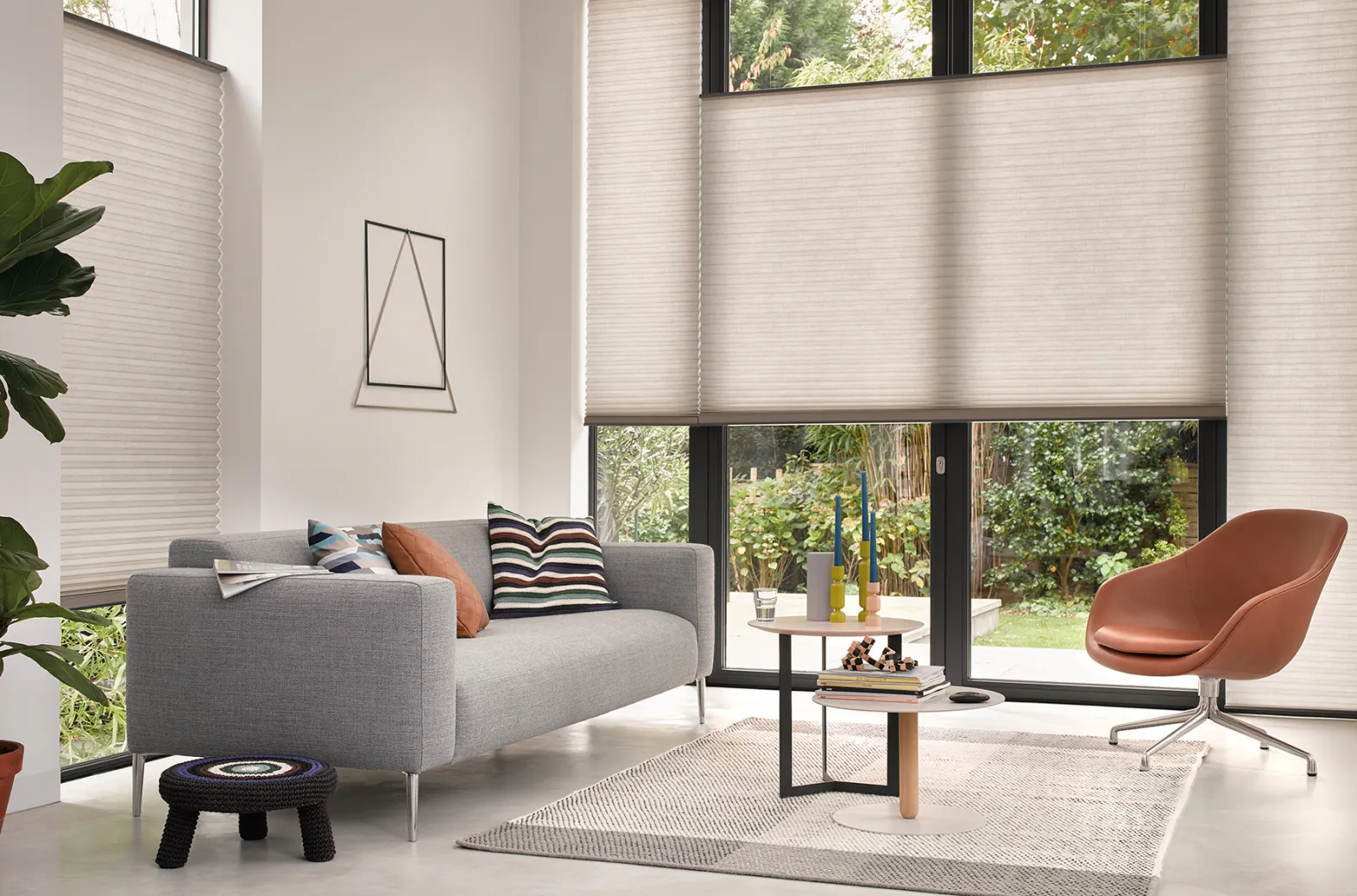 Light beige Duette® honeycomb blinds on floor‑to‑ceiling windows in a modern living room.