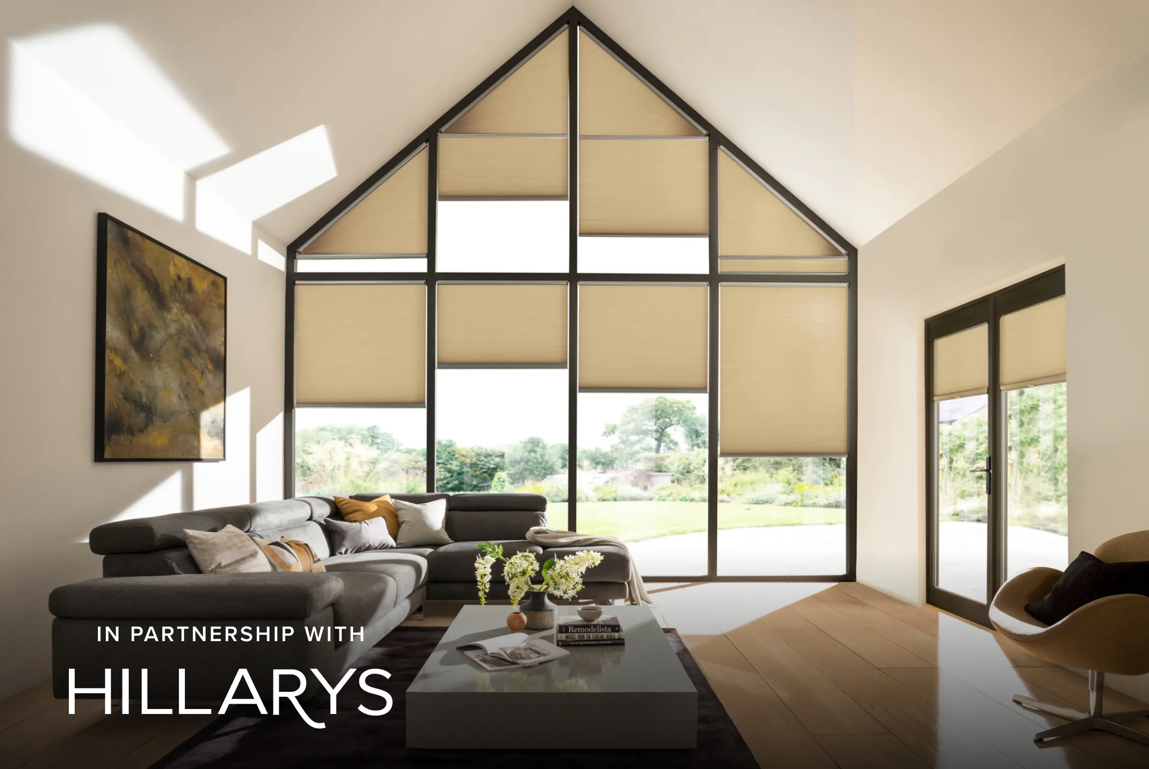 Beige Duette® honeycomb blinds on tall gable‑end windows lighting a modern living room with neutral décor.