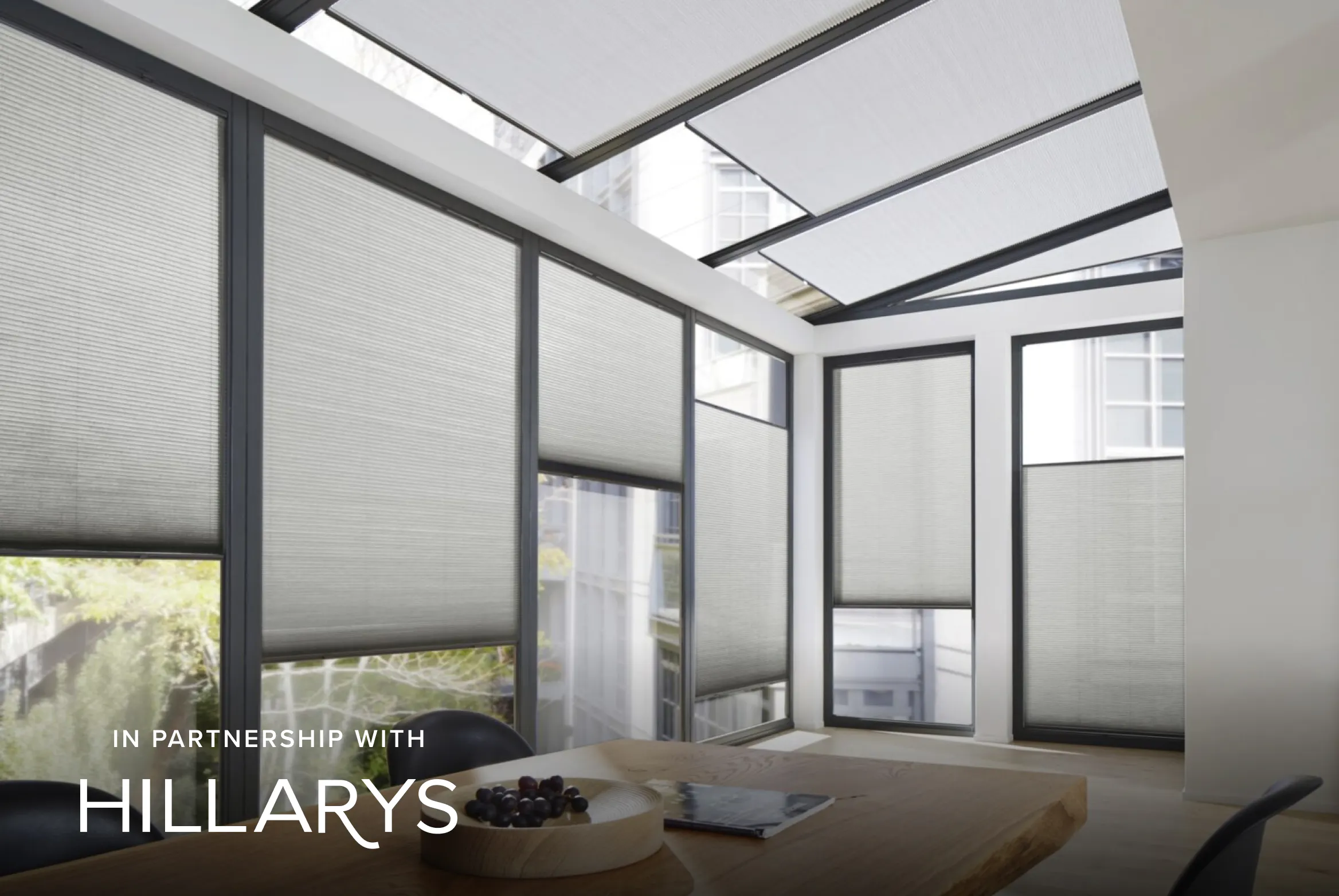 Light grey Duette® honeycomb blinds on patio doors and skylight windows in a bright dining room