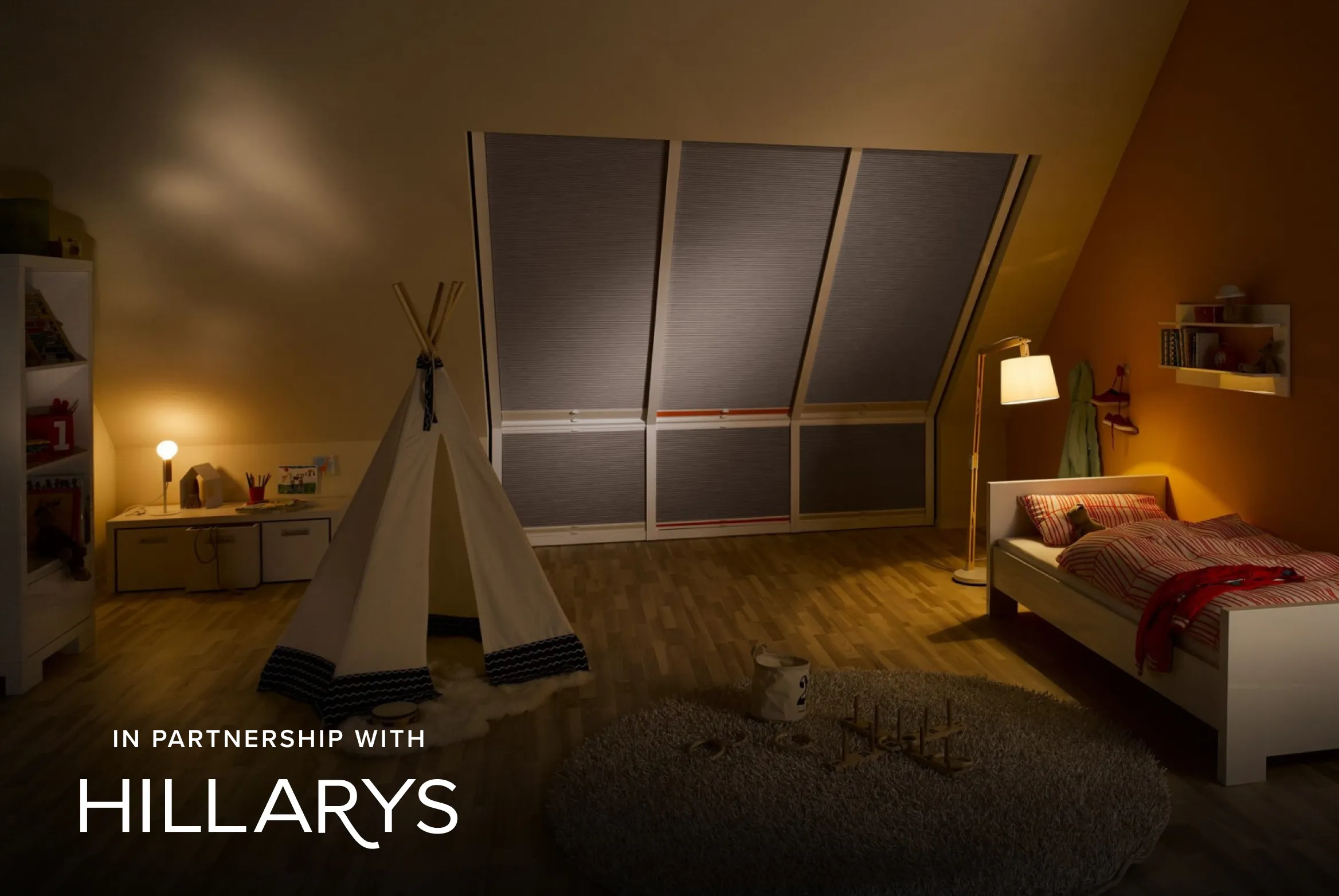 Children’s bedroom at night with fully closed Duette® honeycomb blinds on large slanted windows and warm lighting.