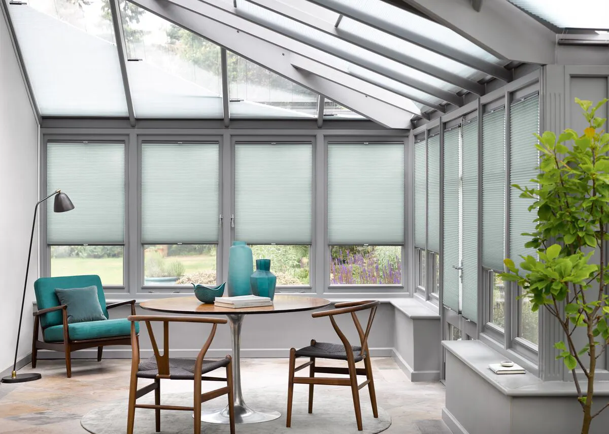 Light grey Duette honeycomb blinds on conservatory roof and windows in a modern grey dining space.