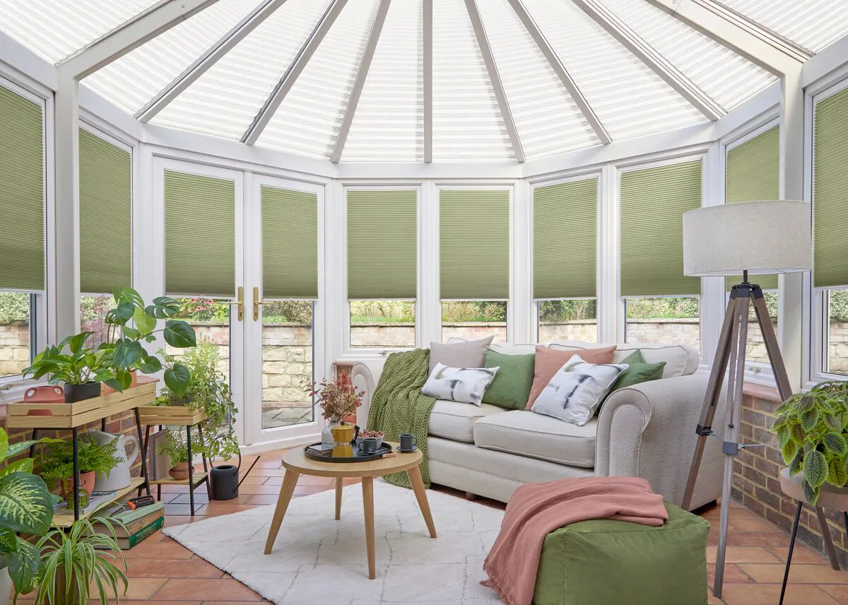Green Duette honeycomb blinds on conservatory windows creating a bright, relaxing seating area.