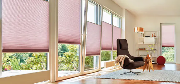 Pink Duette® honeycomb blinds on large windows and a patio door in a light living  room