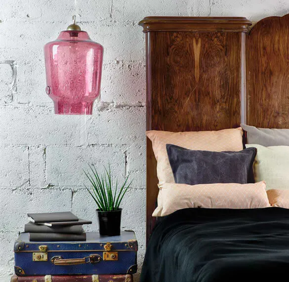 Bed with multicoloured pillows and a pink lap above it