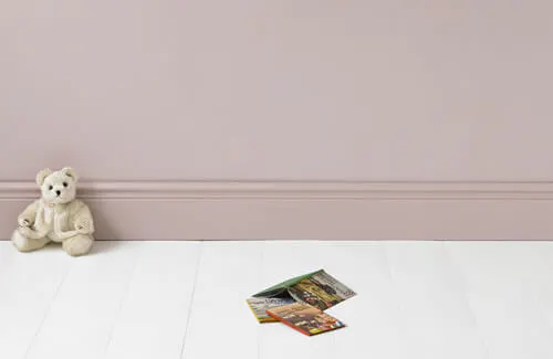 White teddy bear in front of a pink pastel wall