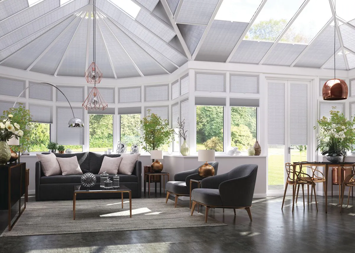Light grey Duette honeycomb blinds on conservatory roof and windows in a spacious living and dining area with modern décor.