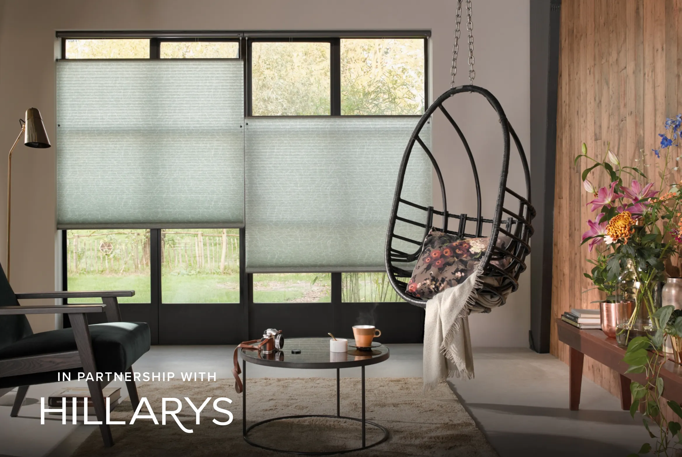 Green Duette® honeycomb blinds on large patio doors in a modern living room with a hanging chair.