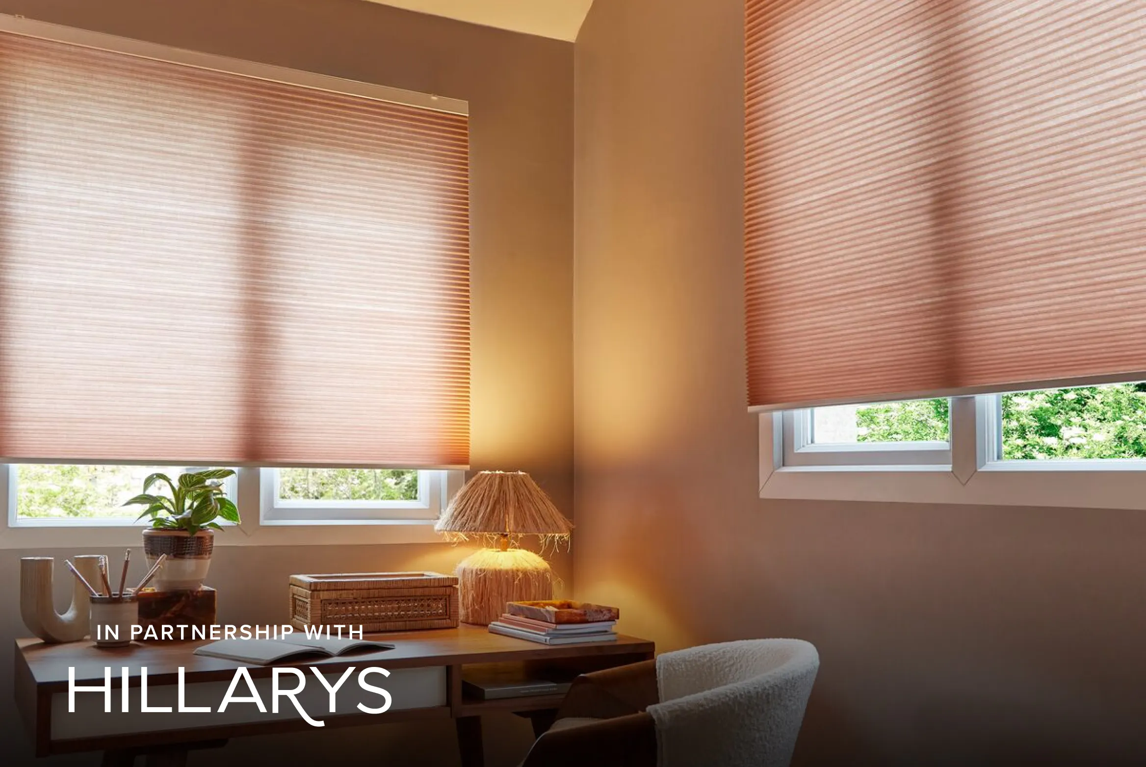 Soft pink Duette® honeycomb blinds on windows in a cosy home office