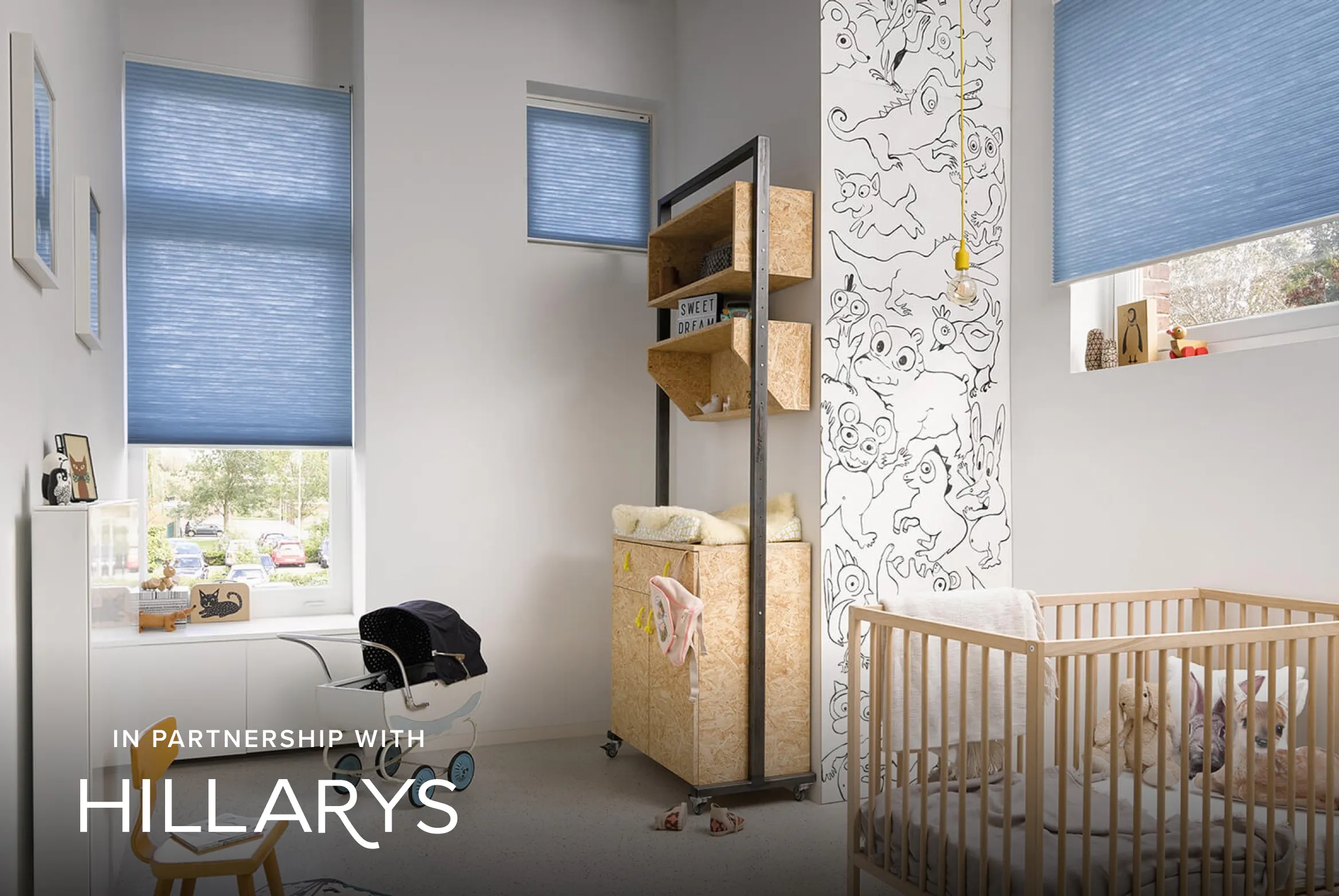 Light blue Duette® honeycomb blinds in a bright nursery with wooden furniture.