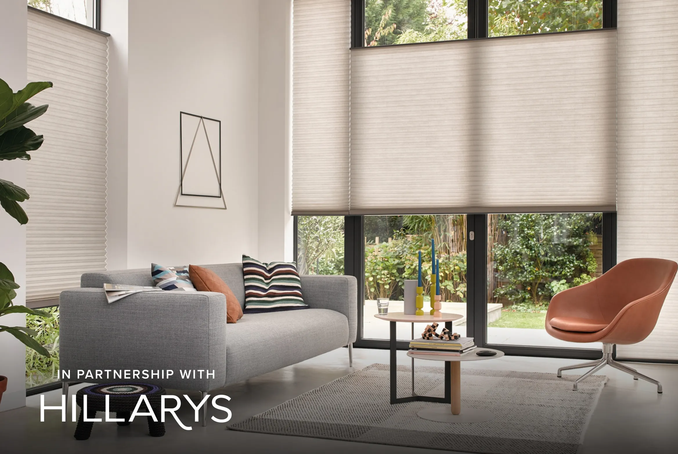 Light beige Duette® honeycomb blinds on floor‑to‑ceiling windows in a modern living room.