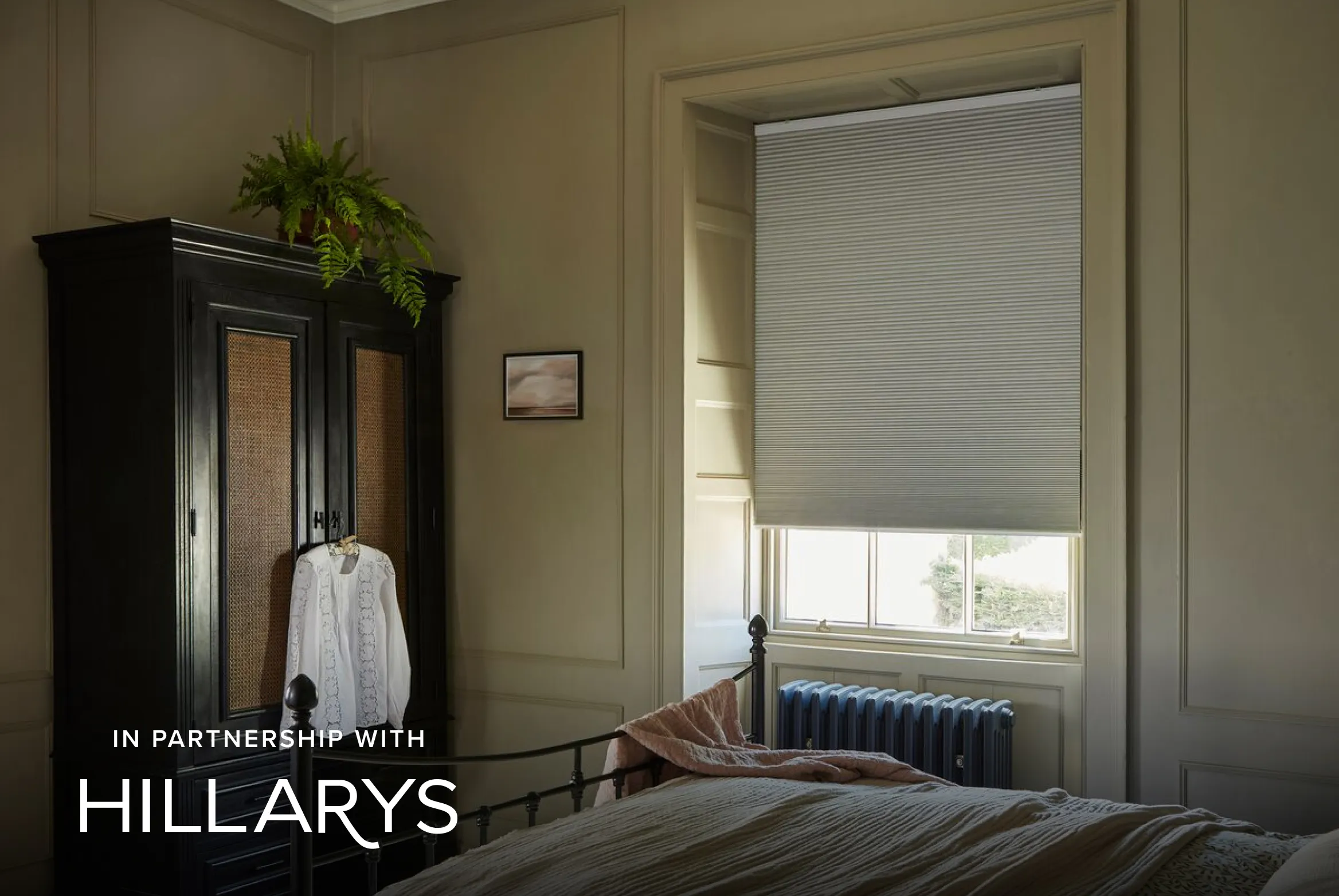 Slightly opened soft grey  Duette® honeycomb blinds in a bedroom with a wooden closet 