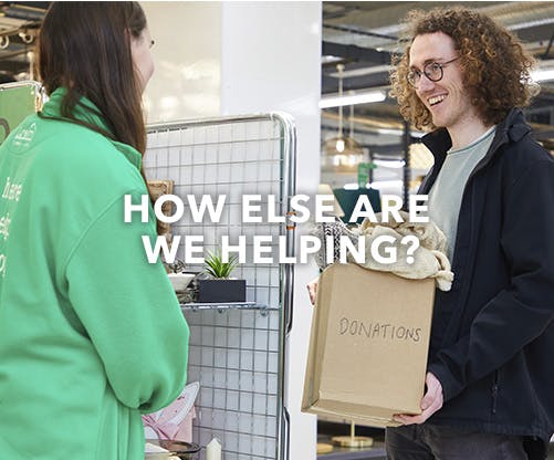 Two people standing and talking. One has a donation box in his hand