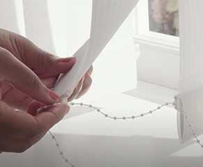 15. Lastly, you need to fit the stabilising chain. Starting at one end of the blind, keeping the vanes parallel, and leaving roughly 10cm of cord in between the vanes. Repeat this on both sides of the blind. 