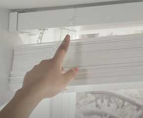 6. Your blind will come with either double-sided sticky patches or plastic clips. Space them evenly along the headrail and then attach the valance.