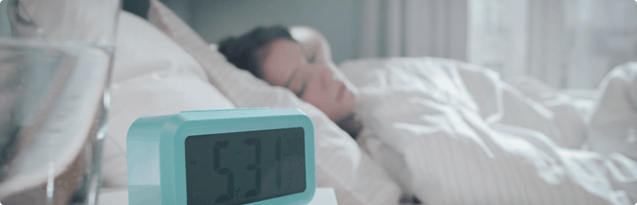 Student in bed with alarm clock set