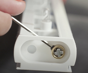 4. Lay the blind headrail on the floor with the base facing upwards, and identify the wand control end. Without removing the rubber band, loosen the locking ring at the opposite end of the wand with the supplied Allen key. 