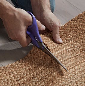 A person cutting a stair runner with scissors