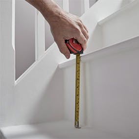 A person measuring a stair riser with a tape measure
