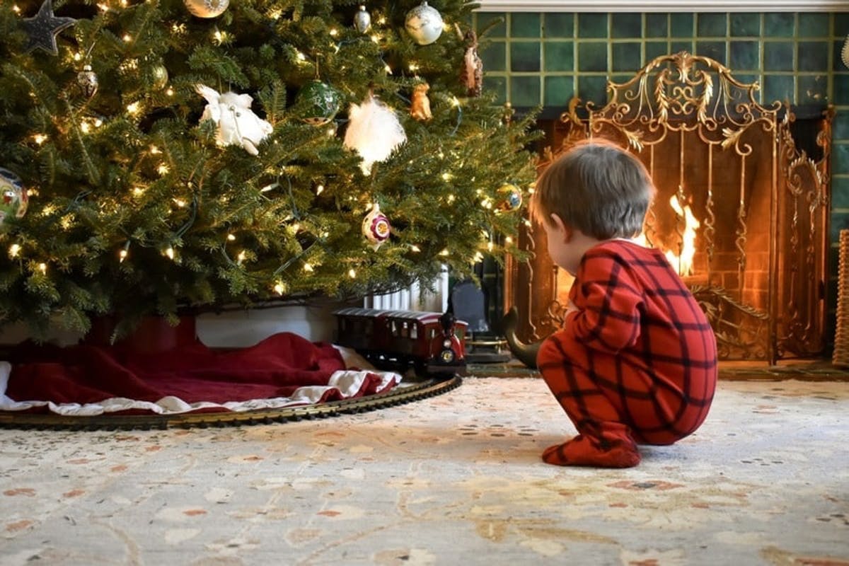  petit garçon dans un pyjama en flanelle au pied d'un arbre de Noël