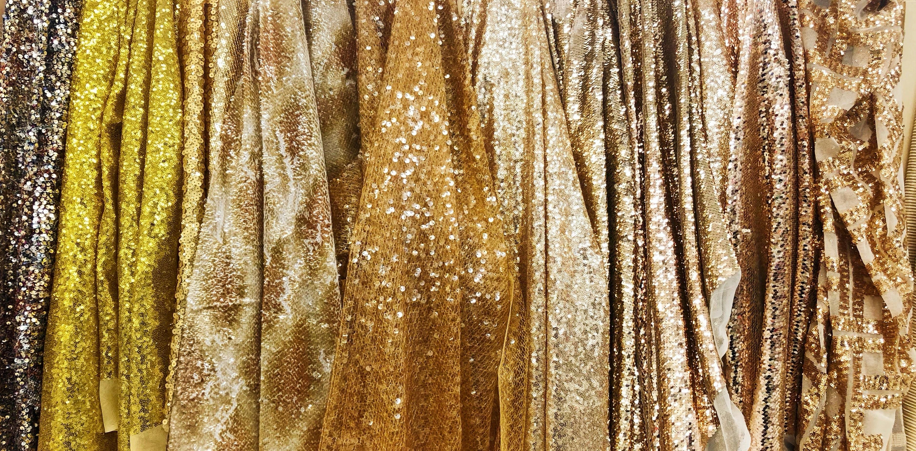  photograph of different gold sequin fabrics hung up