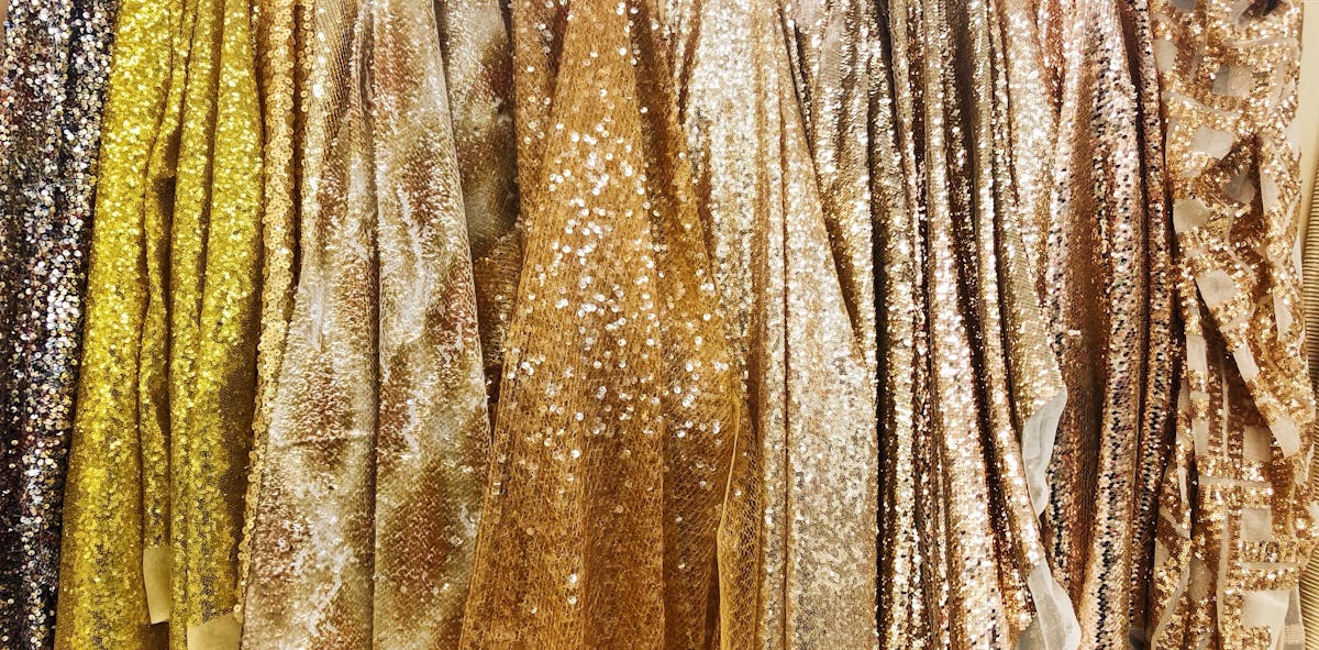  photograph of different gold sequin fabrics hung up