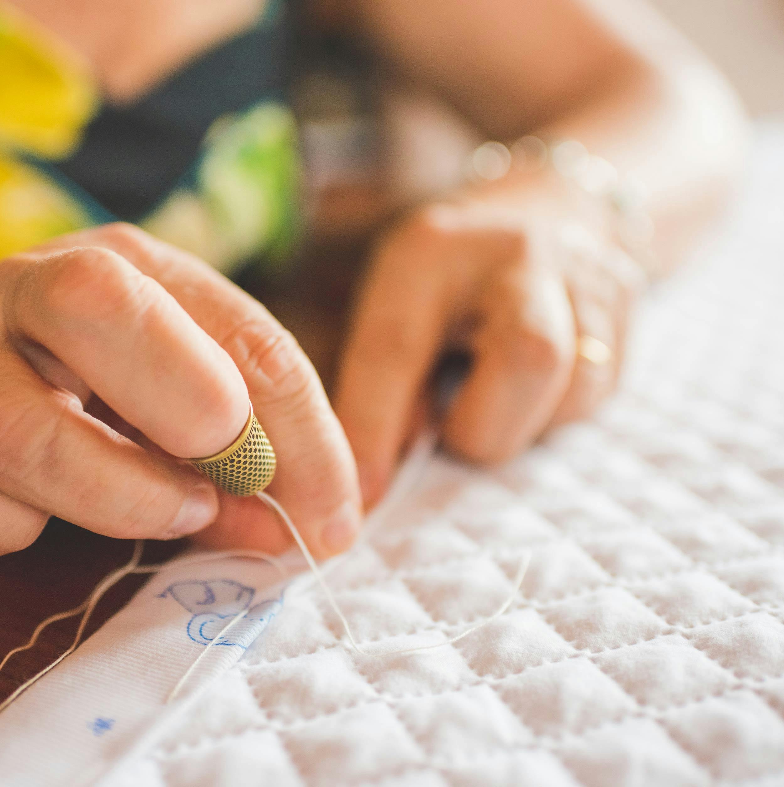  white quilt with woman hand sewing on edge binding