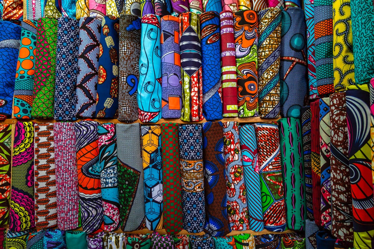  brightly colored printed fabrics folded in piles